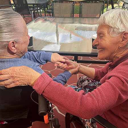 Two residents enjoy time together in courtyard
